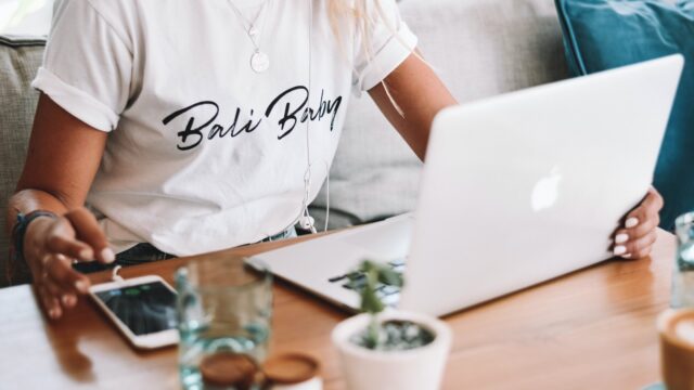 woman in white crew neck t-shirt sitting by the table with macbook